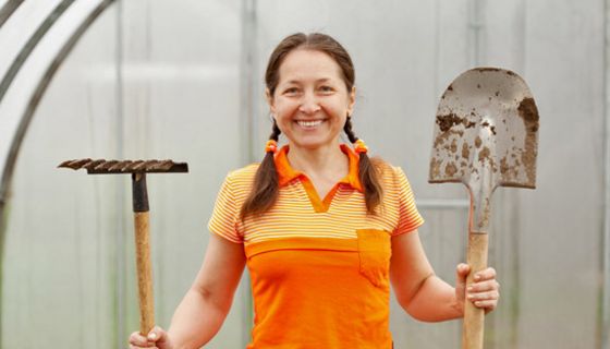 Frau hält Schaufel und Harke.