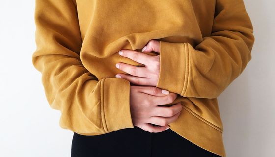 Frau, hält mit beiden Händen ihren Unterleib.