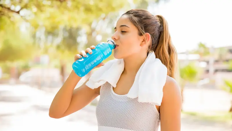 Sportlerin trinkt aus einer Flasche.