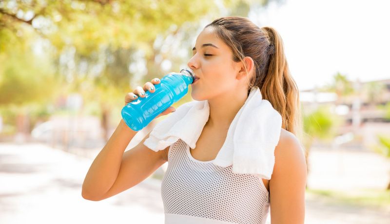 Sportlerin trinkt aus einer Flasche.