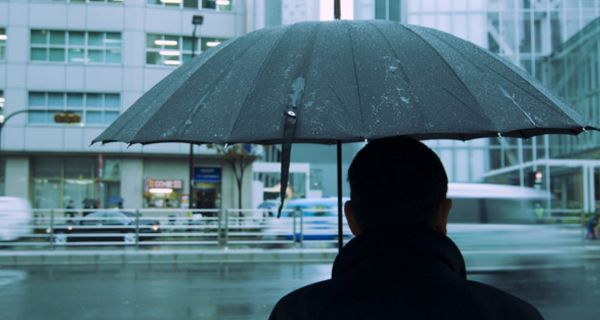 Mann unter Regenschirm bei Schmuddelwetter