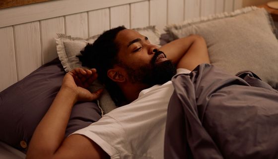 Ein Mann schläft in einem Bett.