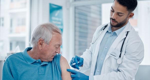 Arzt impft älteren Patienten.