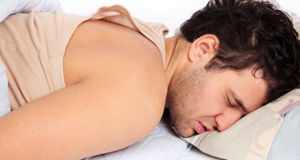 Junger Mann mit Bart schläft auf dem Bauch