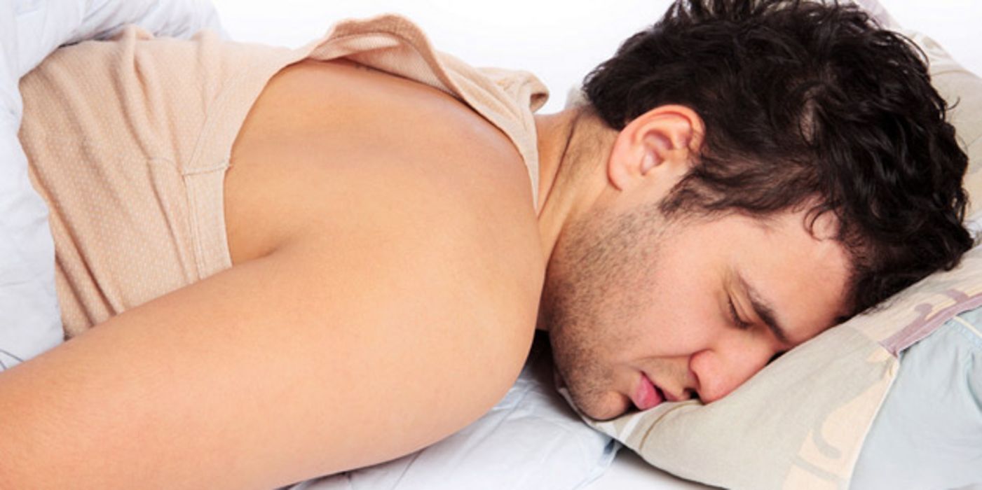 Junger Mann mit Bart schläft auf dem Bauch