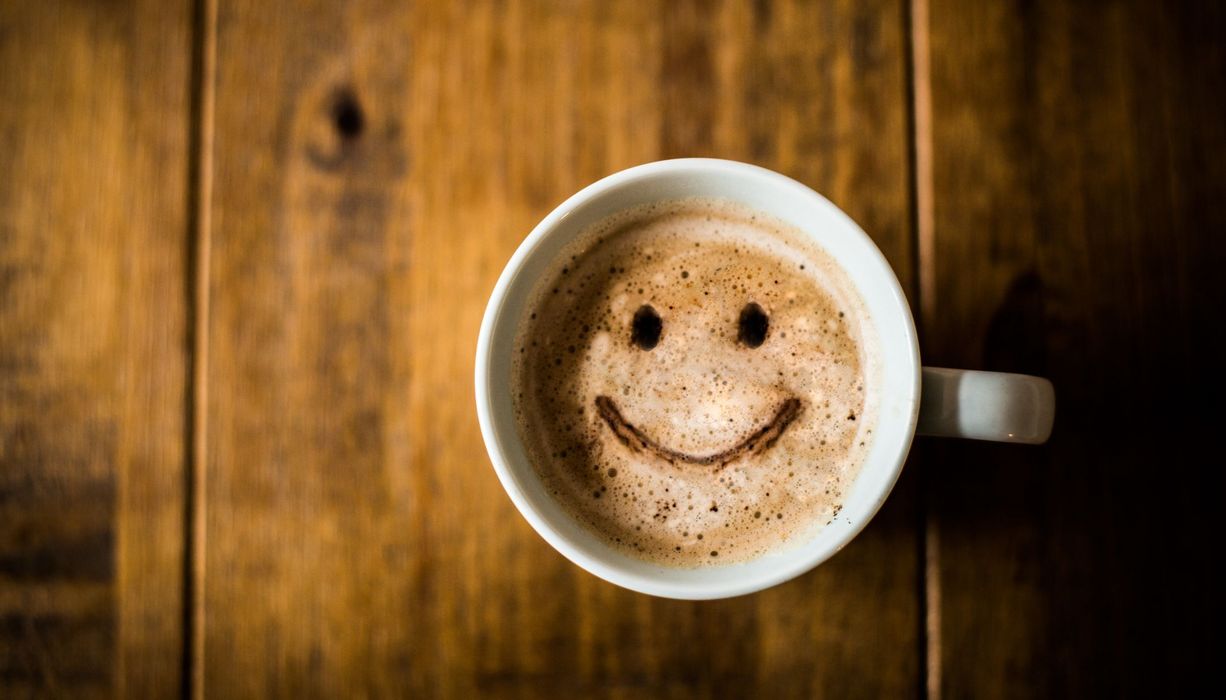 Tasse Kaffee mit lächelndem Gesicht.