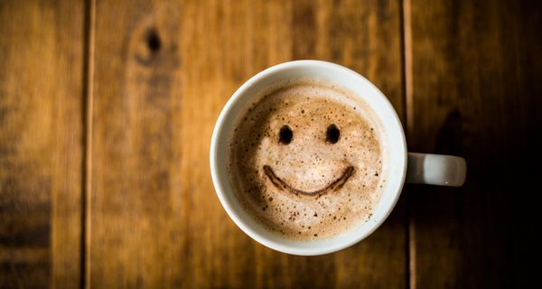 Tasse Kaffee mit lächelndem Gesicht.
