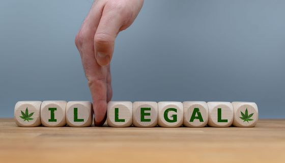 Symbol für die Legalisierung von Marihuana. Würfel bilden das Wort "ILLEGAL", während eine Hand die Buchstaben "IL" trennt, um das Wort in "LEGAL" zu ändern.