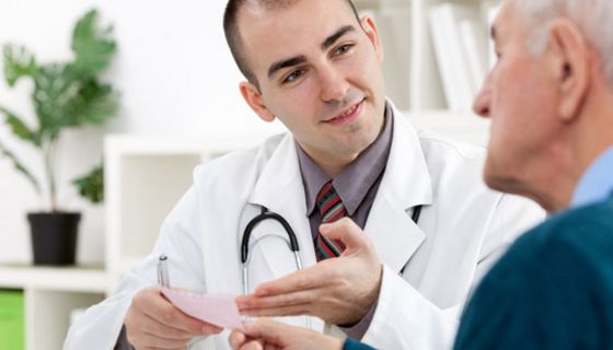 Arzt händigt älterem Patienten ein Rezept aus.