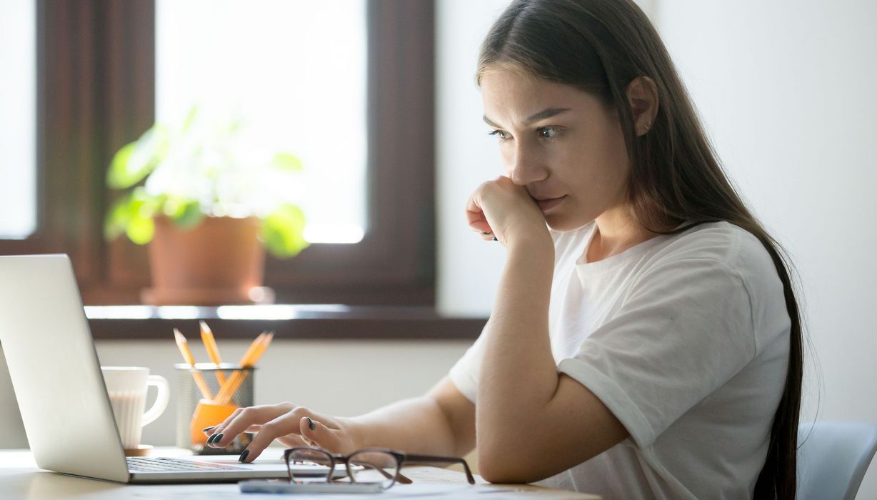 Junge Frau, sitzt vor ihrem Laptop.