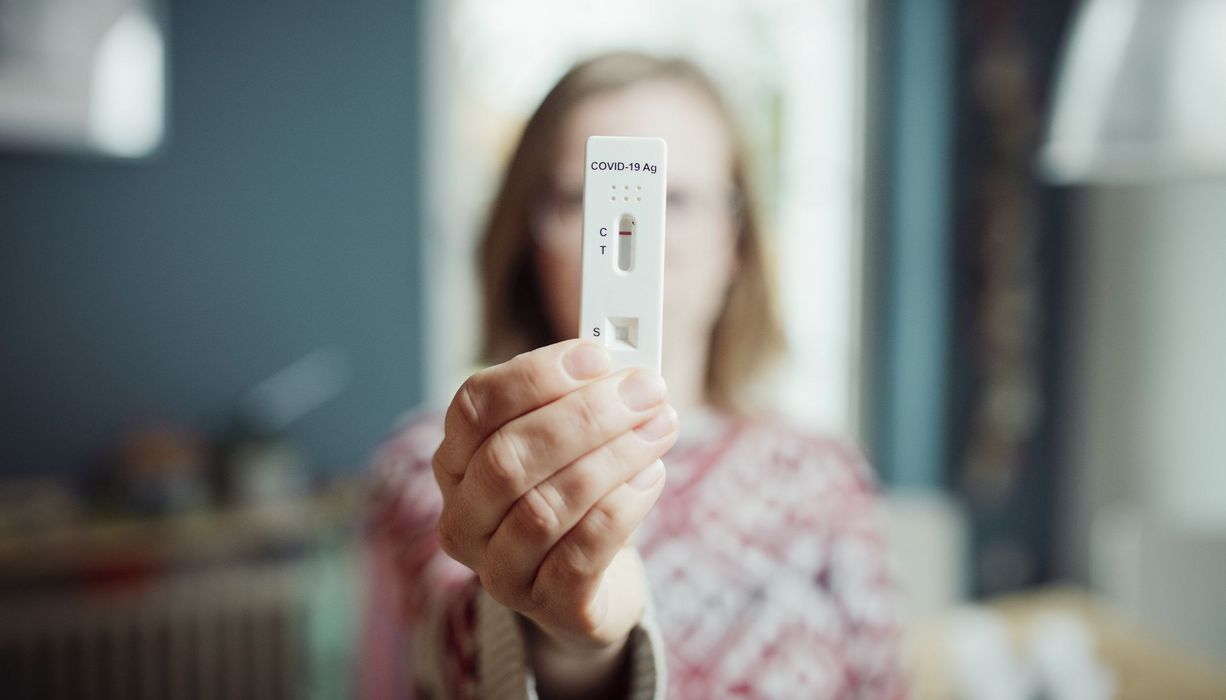 Frau, hält Corona-Schnelltest in die Kamera.