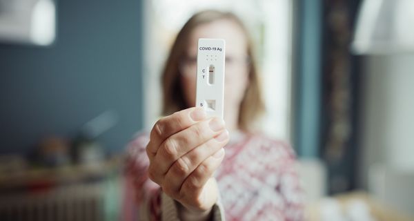 Frau, hält Corona-Schnelltest in die Kamera.