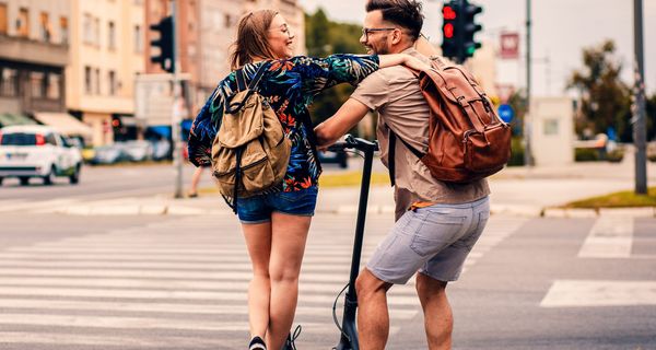 Ein junges Pärchen, fährt mit E-Rollern durch die Stadt.