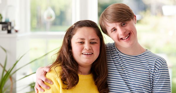 Eine junge frau und ein junger Mann mit Down-Syndrom umarmen sich.