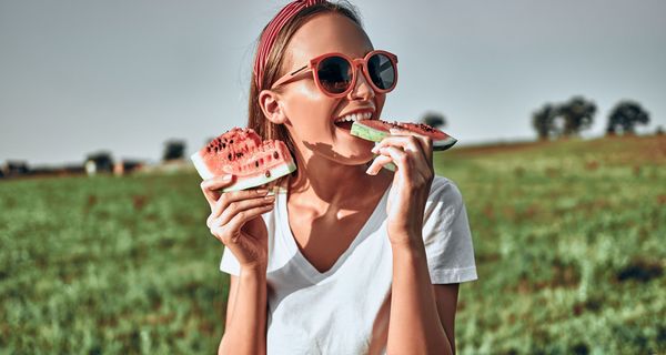 Junge Frau, beißt von einer Wassermelone ab.