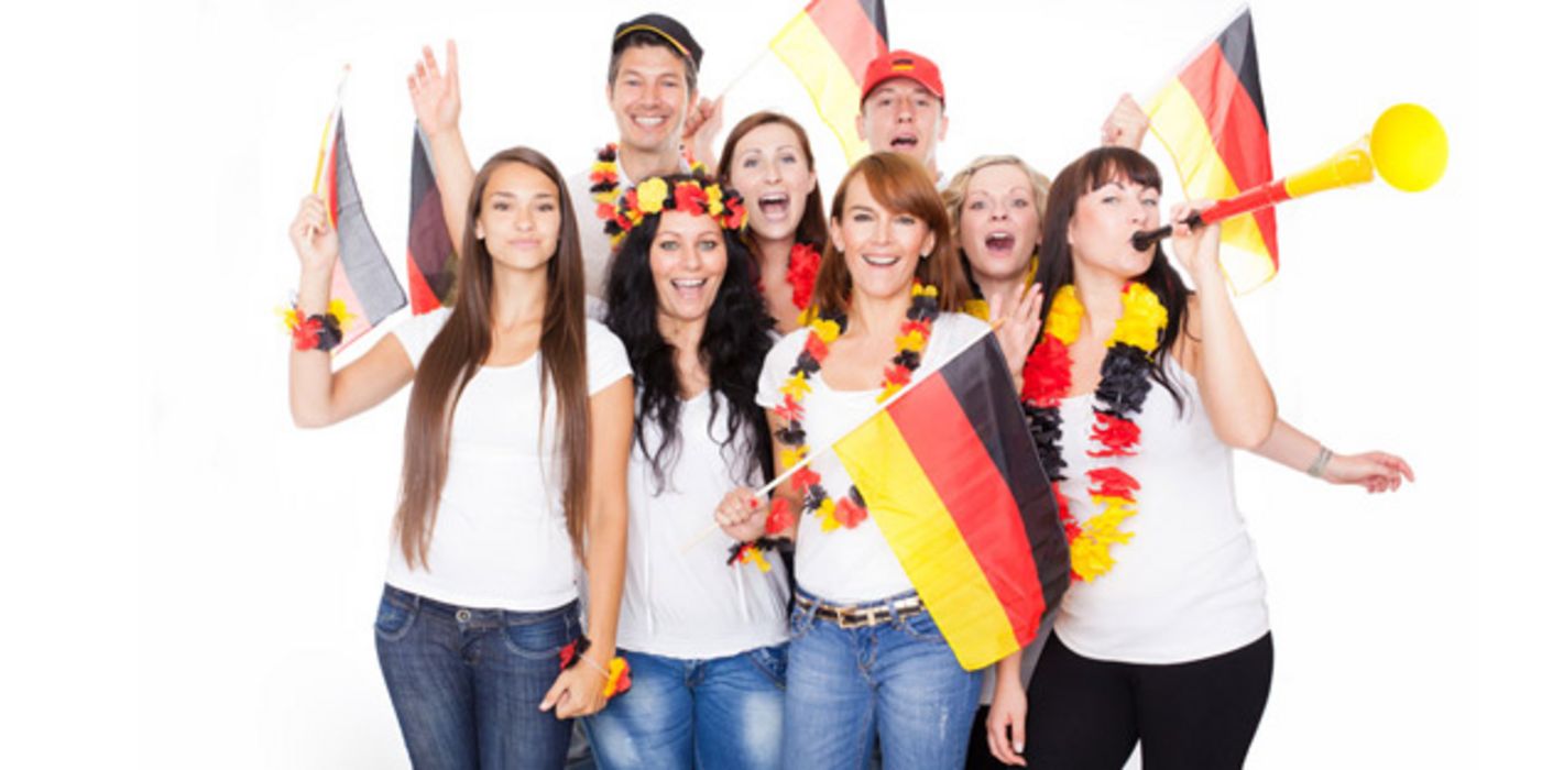 Junge Fußballfans mit Fähnchen, Tröte und Blumenketten in Deutschlandfarben