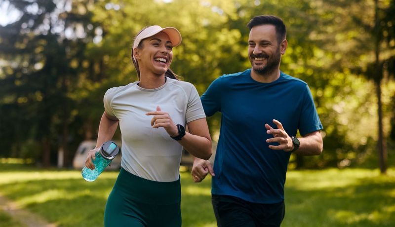 Junge Frau und junger Mann joggen zusammen im Park.