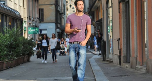 Junger Mann läuft eine Straße entlang und hört Musik mit einem MP3-Player