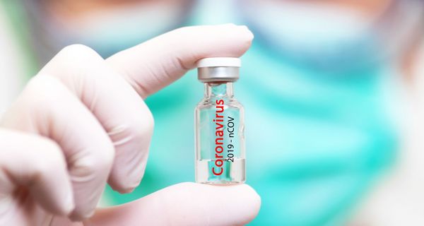 Forscher hält eine Dosis Corona-Impfstoff zwischen den Fingern.