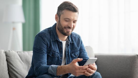 Junger Mann tippt auf seinem Handy.