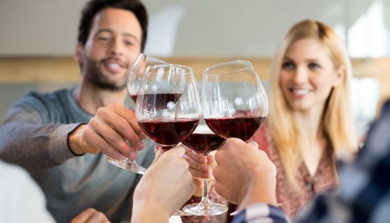 Eine Gruppe junger Leute prostet sich mit Rotwein zu.