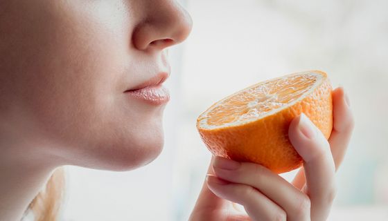Frau riecht an halbierter Orange.