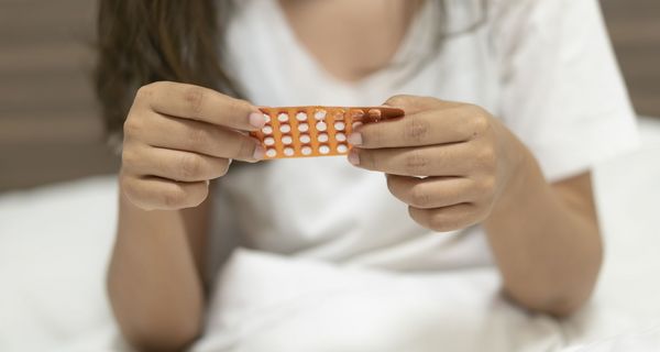 Eine Frau hält mit ihren Händen einen Monatsblister von der Minipille in der Hand.