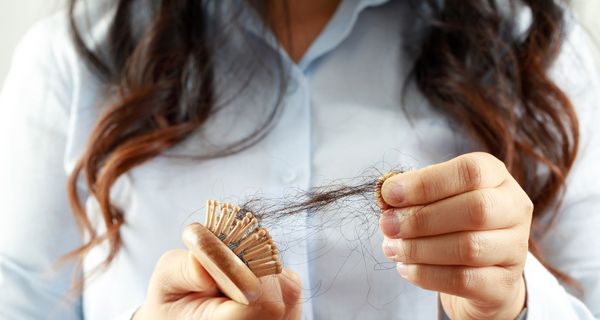 Frau, zieht Haare aus ihrer Bürste.