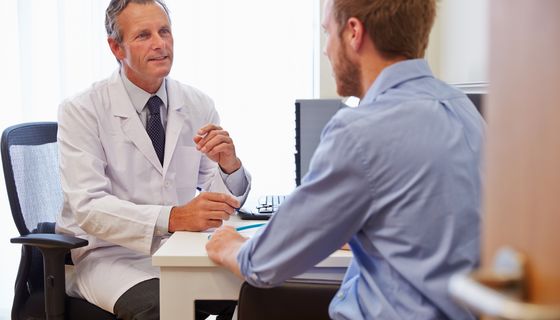 Mann unterhält sich mit Arzt.
