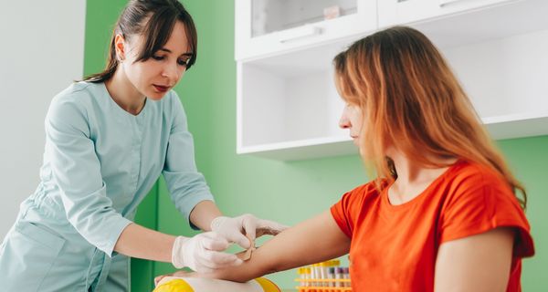 Arzthelferin nimmt einer Frau Blut ab.
