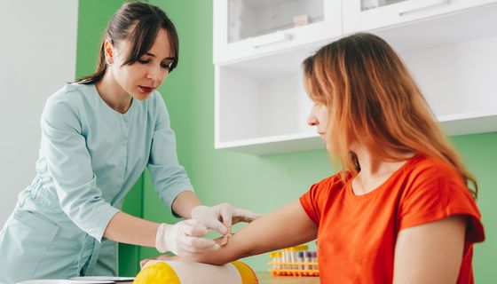 Arzthelferin nimmt einer Frau Blut ab.