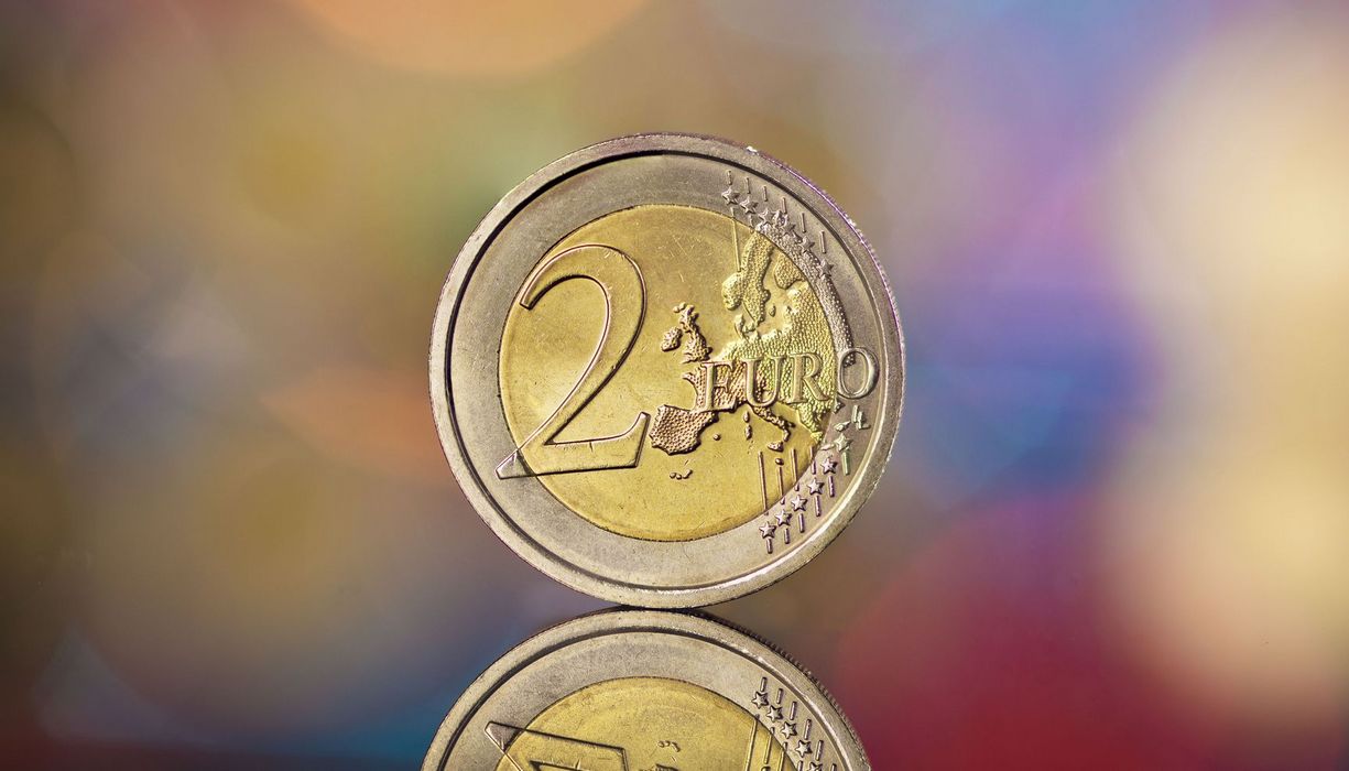 Zwei Euro Münze auf buntem, verschwommenem Hintergrund.