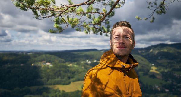 Mann in Regenkleidung, vor bewölktem Himmel.