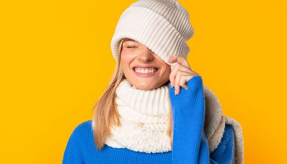 Junge Frau mit dickem Schal zieht sich eine Mütze ins Gesicht.