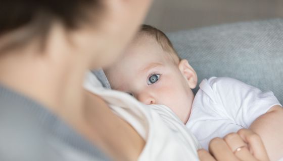 Ein Baby, das gestillt wird, schaut in die Kamera.