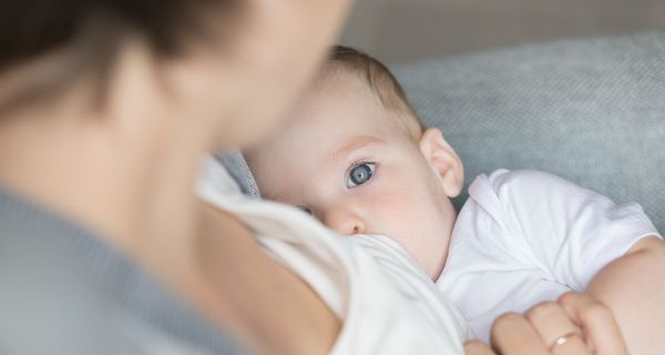 Ein Baby, das gestillt wird, schaut in die Kamera.