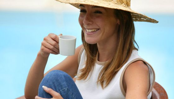 Lachende Frau mit Hut und Kaffeetasse