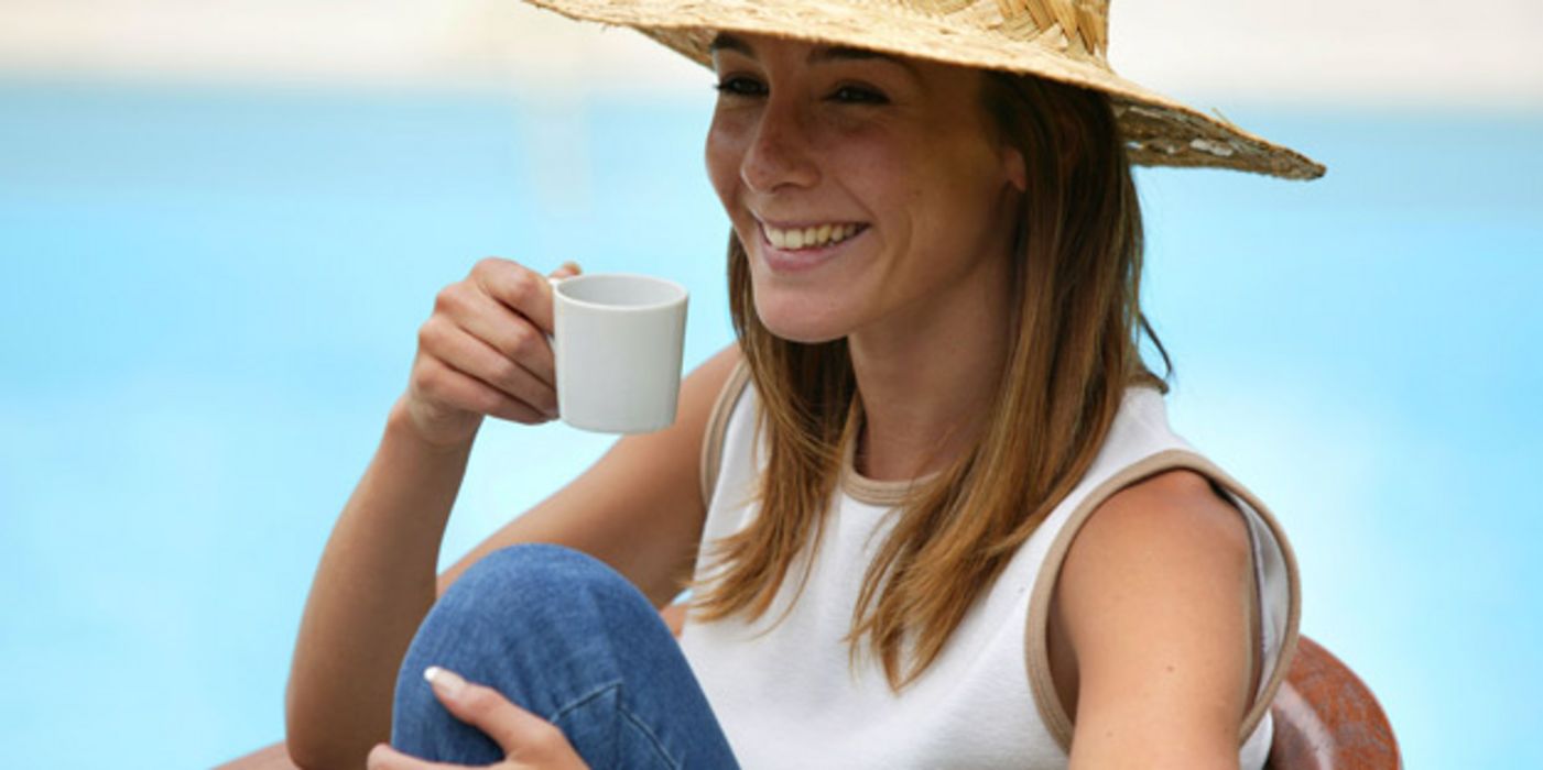 Lachende Frau mit Hut und Kaffeetasse