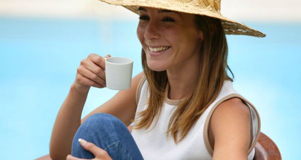 Lachende Frau mit Hut und Kaffeetasse