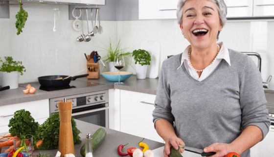 Seniorin schneidet Gemüse in der Küche.