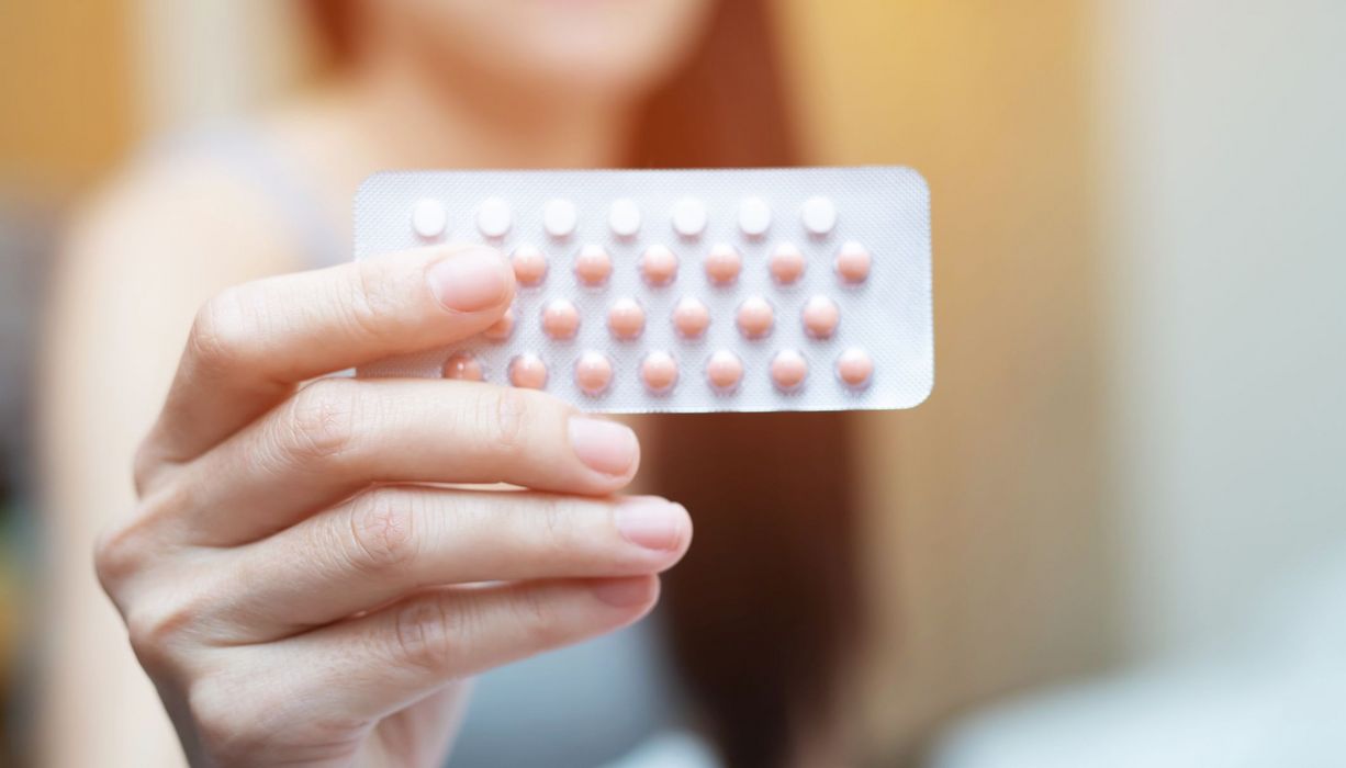 Frau, hält einen Blister mit Antibabypillen in der Hand.