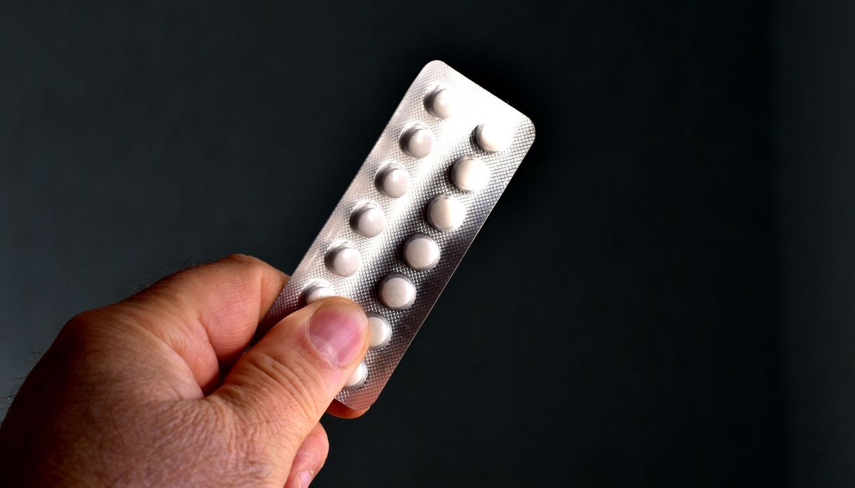Mann, hält ein Blister Tabletten in der Hand.