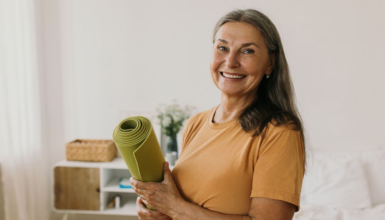 Ältere Frau mit Yogamatte