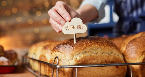 Eine Frau streckt ein glutenfrei-Schildchen auf ein Brot.