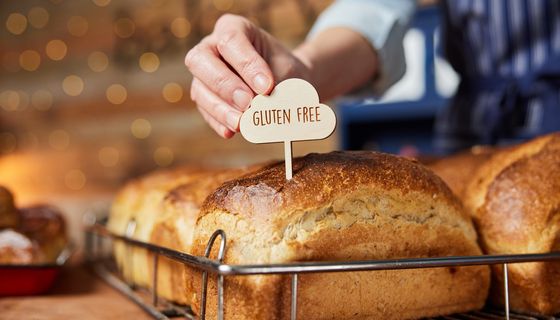 Eine Frau streckt ein glutenfrei-Schildchen auf ein Brot.