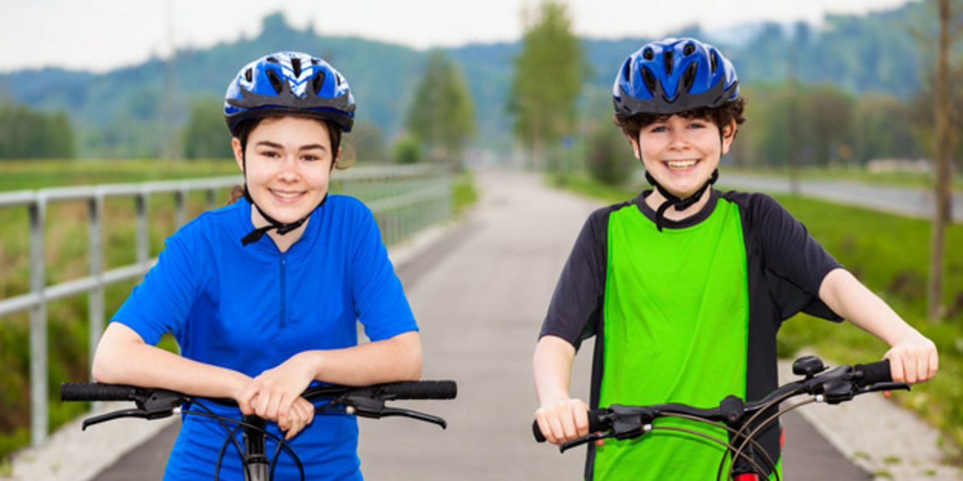 Zwei lächelnde Mädchen mit Fahrradhelmen.