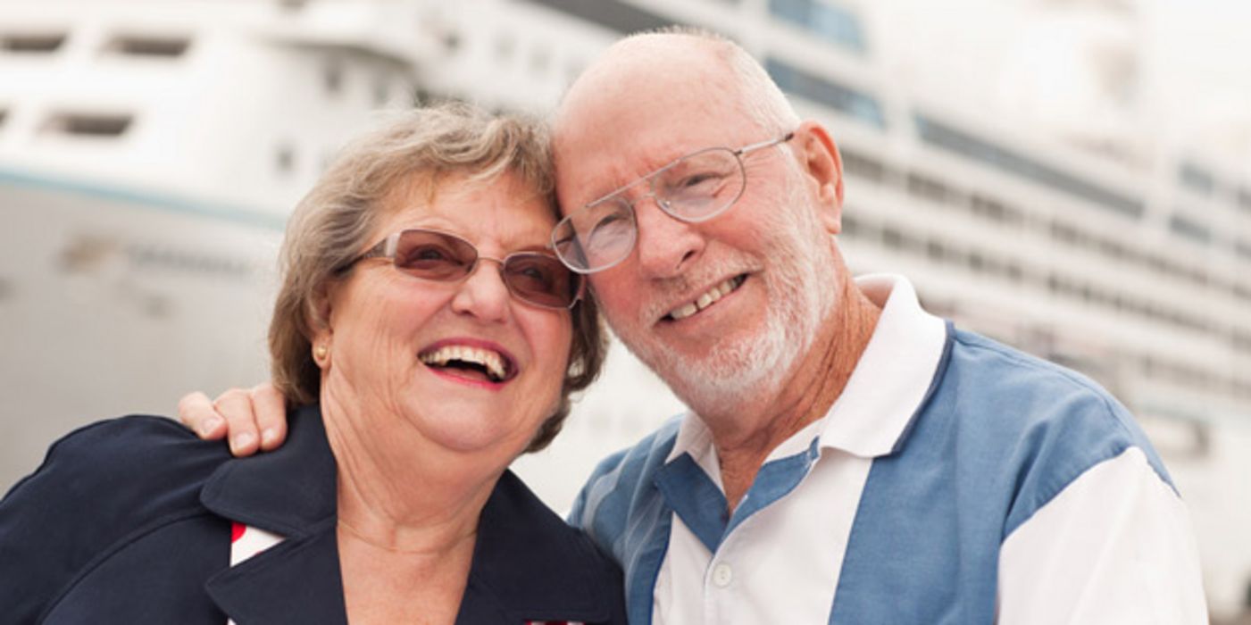Fröhliches Rentnerpaar vor Kreuzfahrtschiff