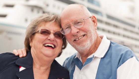 Fröhliches Rentnerpaar vor Kreuzfahrtschiff
