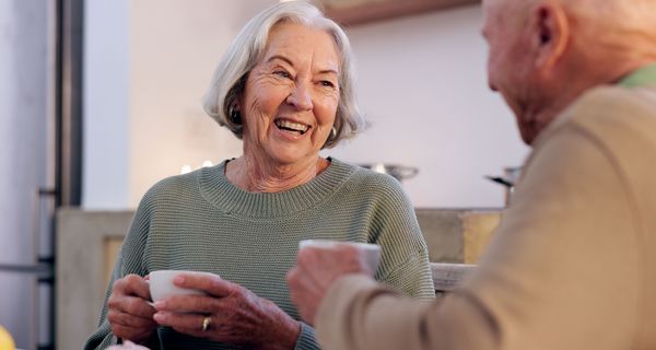 Ältere Frau und älterer Mann halten eine Kaffeetasse in der Hand