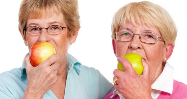 Zwei Seniorinnen beißen in Äpfel